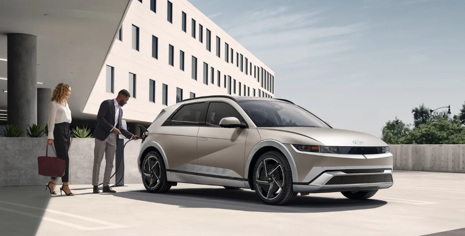Man charging Hyundai IONIQ 5 while standing with woman.