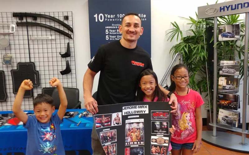 Peter's Special Project and UFC Champion Max Holloway posing with local youth
